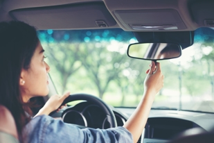 woman adjusting rear view mirror