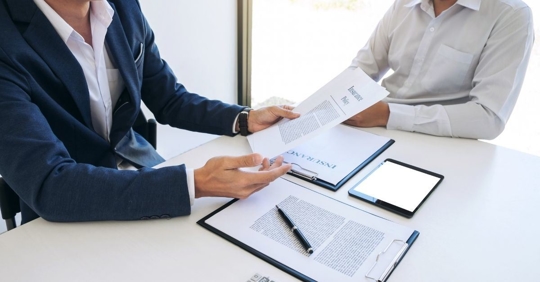 two men in business attire looking at documents titled "insurance policy"