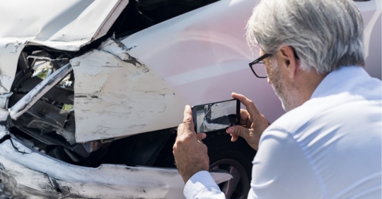 Businessman surveying damage from vehicle after an accident in the company car.