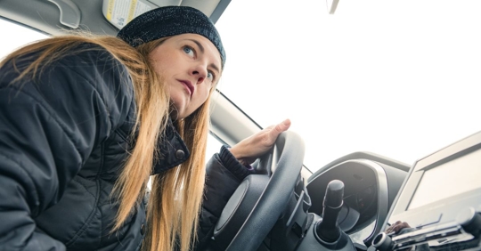 nervous-looking woman sitting in the driver's seat of her car looking out the passenger window