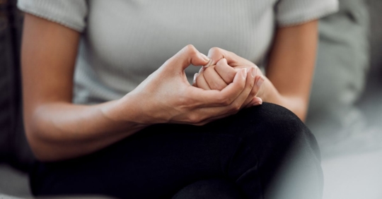 close up of a person sitting on a couch picking at their nail beds
