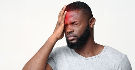 man holding his head with a pained look on his face